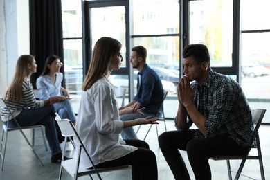 Photo of Psychotherapist working with patient in group therapy session indoors