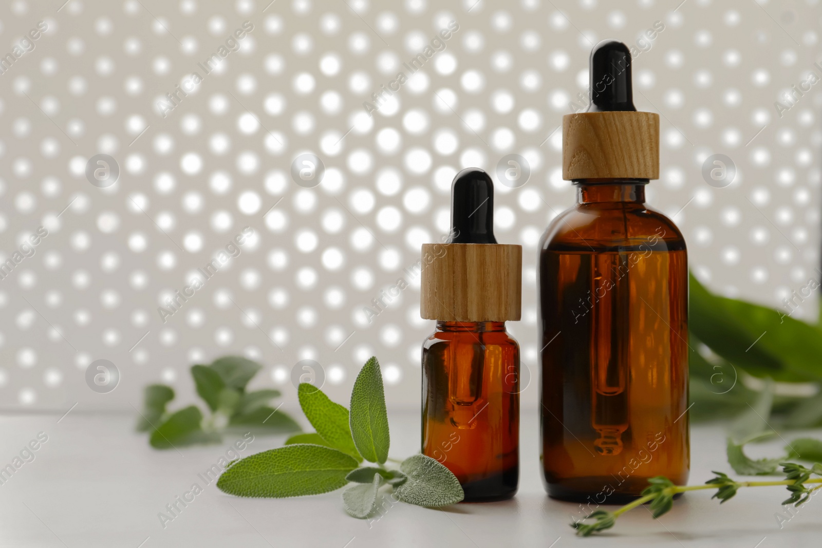 Photo of Bottles of essential oils and fresh herbs on white table, space for text