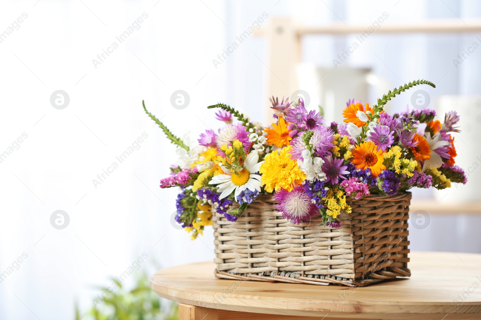 Photo of Wicker basket with beautiful wild flowers on table indoors