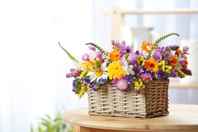 Wicker basket with beautiful wild flowers on table indoors