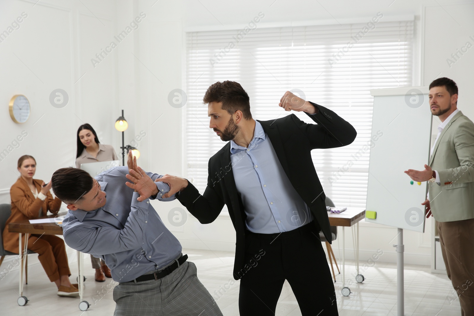 Photo of Emotional colleagues fighting in office. Workplace conflict