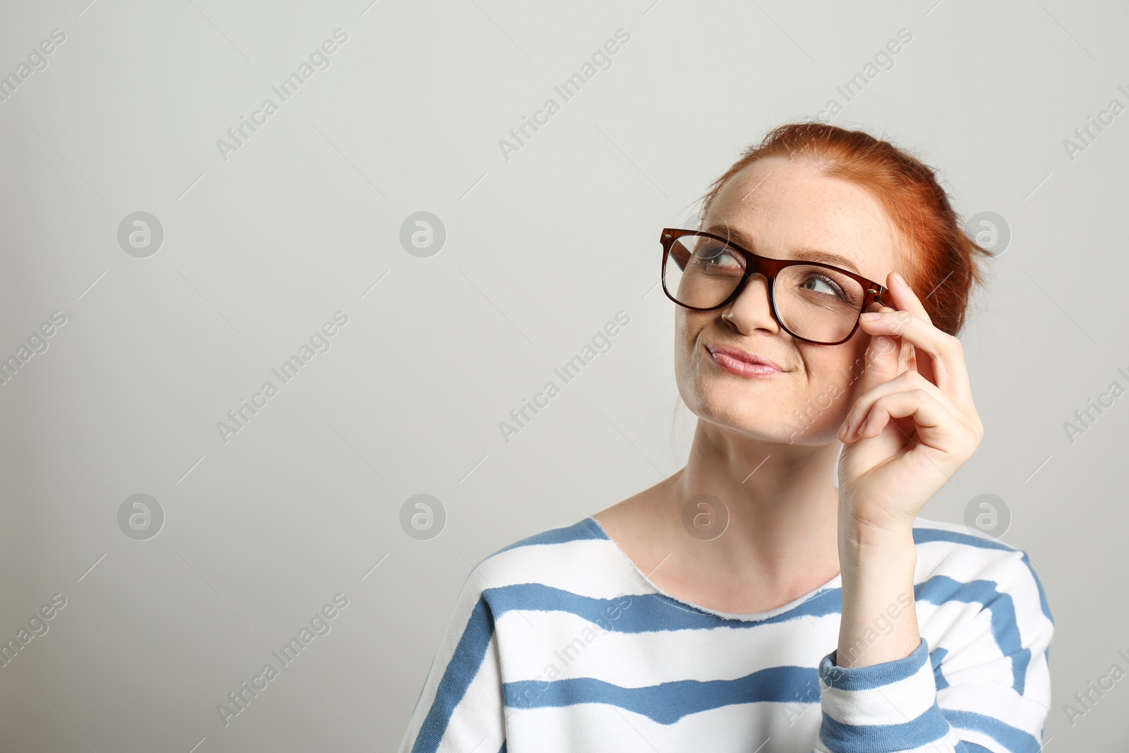 Photo of Portrait of thoughtful red haired woman with glasses on light background, space for text