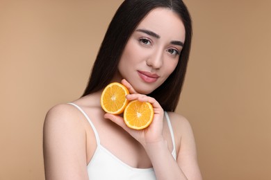 Photo of Beautiful young woman with pieces of orange on beige background