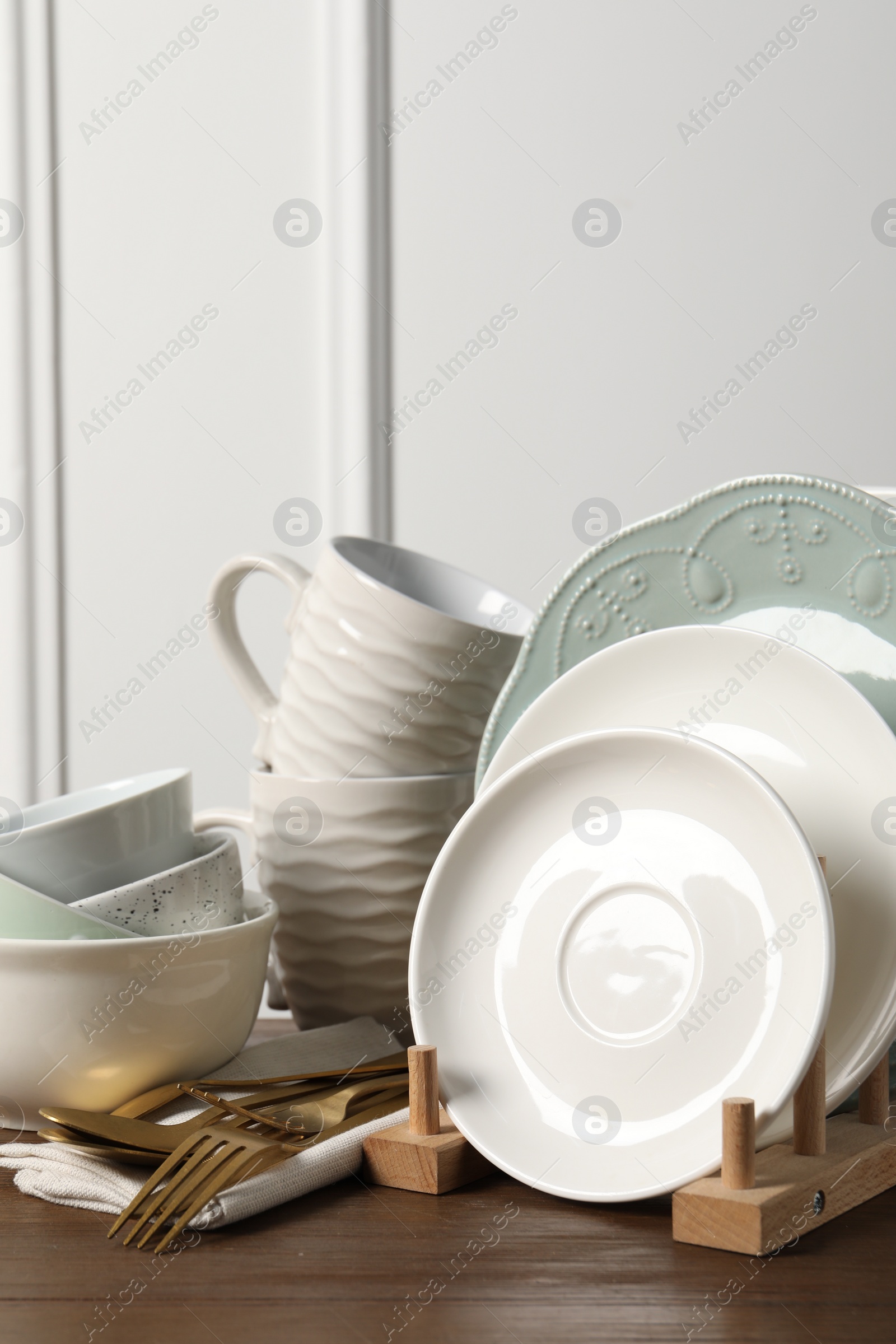 Photo of Beautiful ceramic dishware, cups and cutlery on wooden table