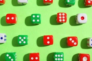 Photo of Many color game dices on green background, flat lay