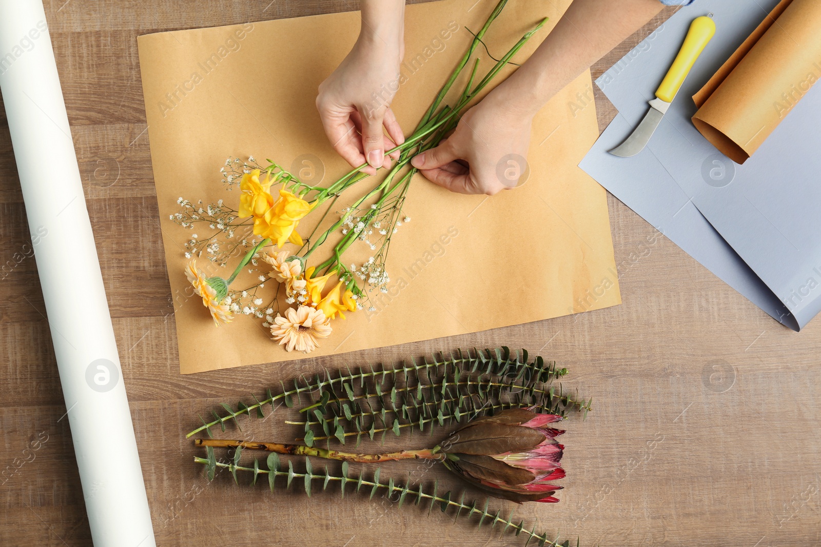 Photo of Female florist making beautiful bouquet at table, top view