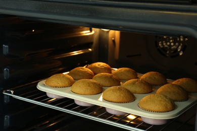Photo of Baking pan with cupcakes in modern oven