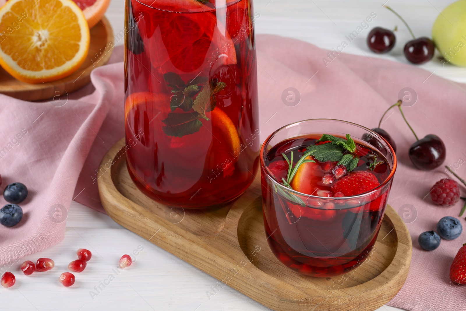 Photo of Delicious refreshing sangria, fruits and berries on white wooden table