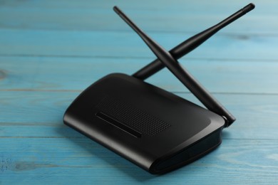 Photo of Modern Wi-Fi router on light blue wooden background