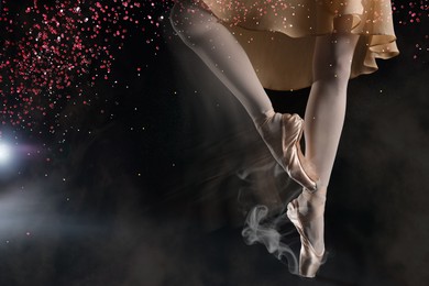Image of Perfection in ballet. Woman dancing in pointe shoes on black background, closeup. Motion effect with smoke and glitter