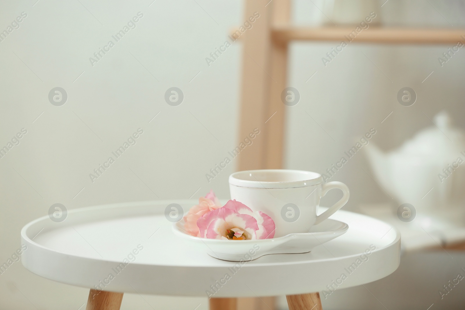 Photo of Cup of tea, saucer and flowers on table indoors