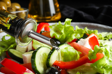 Photo of Adding cooking oil to delicious salad, closeup