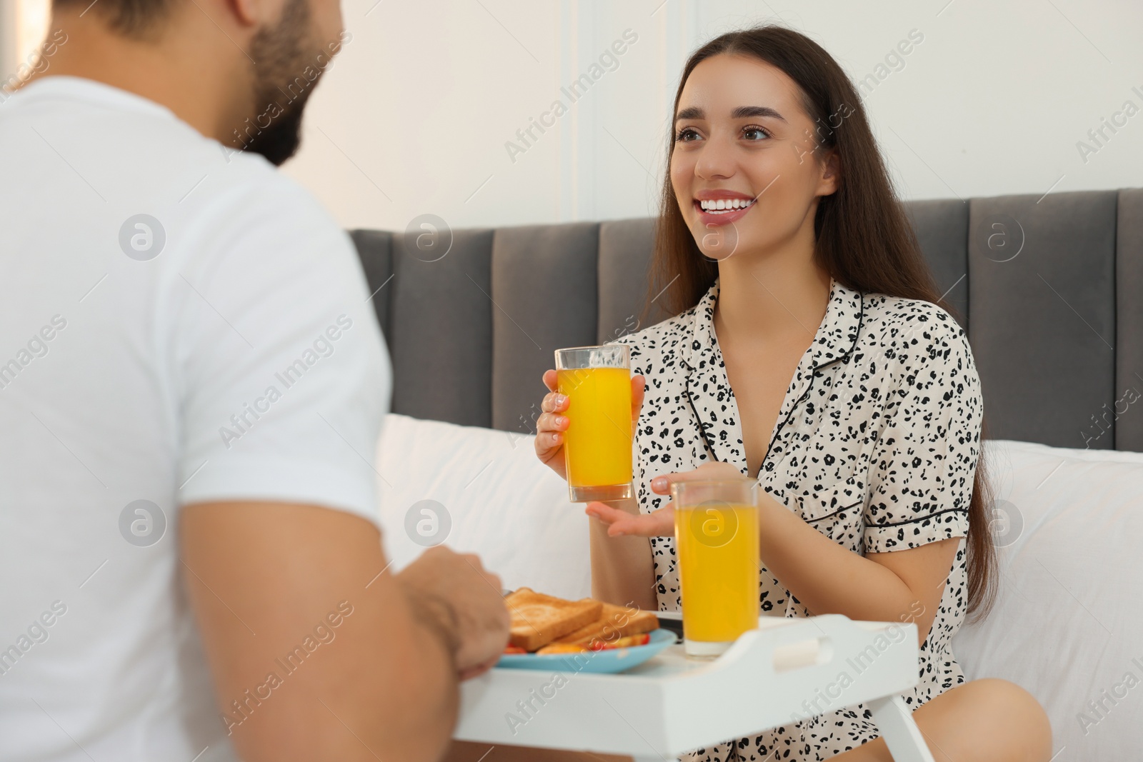 Photo of Happy couple having breakfast on bed at home