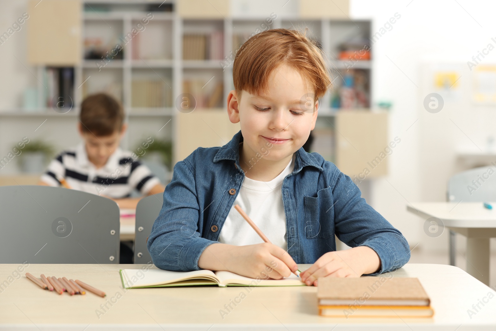 Photo of Portrait of cute little boy studying in classroom at school
