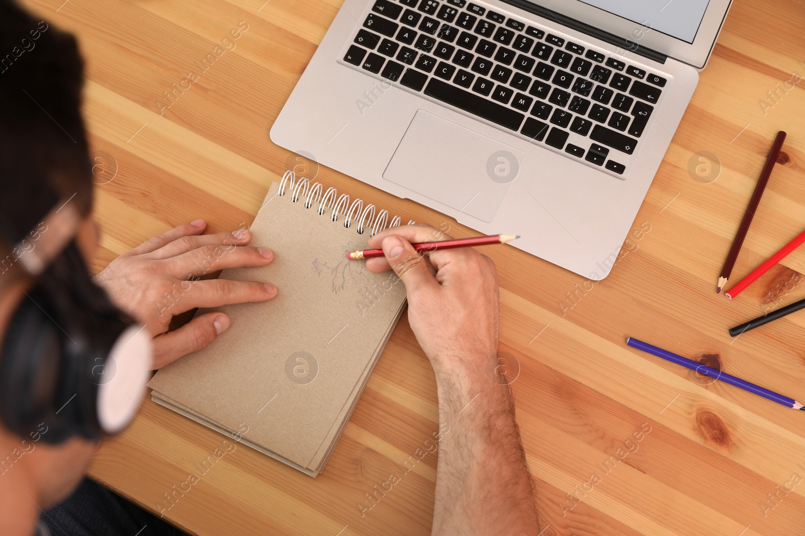 Photo of Man drawing in notebook at table, top view. Distance learning