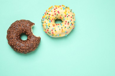 Photo of Delicious glazed donuts on turquoise background, flat lay. Space for text