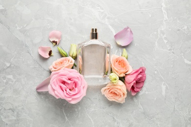 Photo of Flat lay composition with bottle of perfume and fresh flowers on light grey marble background