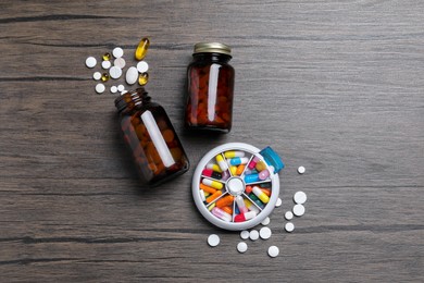 Photo of Pill box with medicaments on wooden table, flat lay