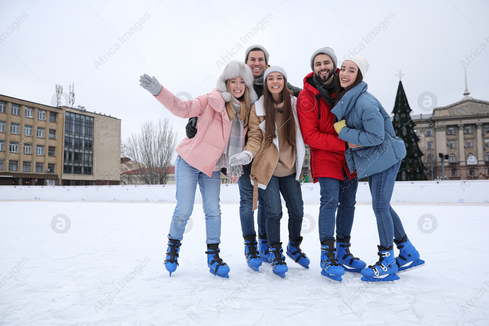 Image of Happy friends at ice skating rink outdoors