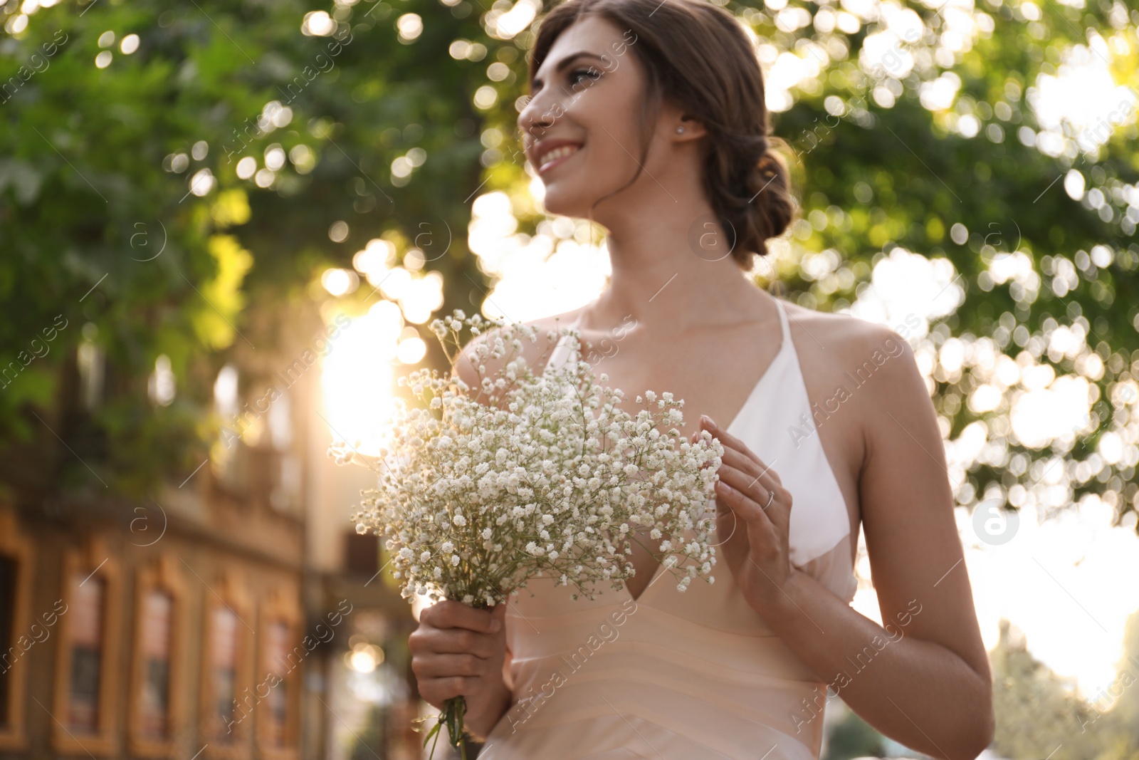 Photo of Gorgeous bride in beautiful wedding dress with bouquet outdoors