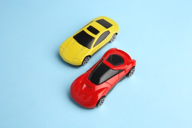 Photo of Two bright cars on light blue background, above view. Children`s toys