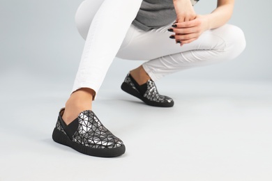 Woman in stylish shoes on grey background, closeup