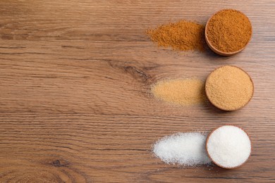 Different types of granulated sugar on wooden table, flat lay. Space for text