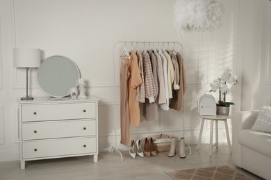 Modern dressing room interior with stylish clothes, shoes and beautiful orchid flowers