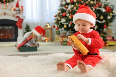 Photo of Cute little boy with toy car in room decorated for Christmas