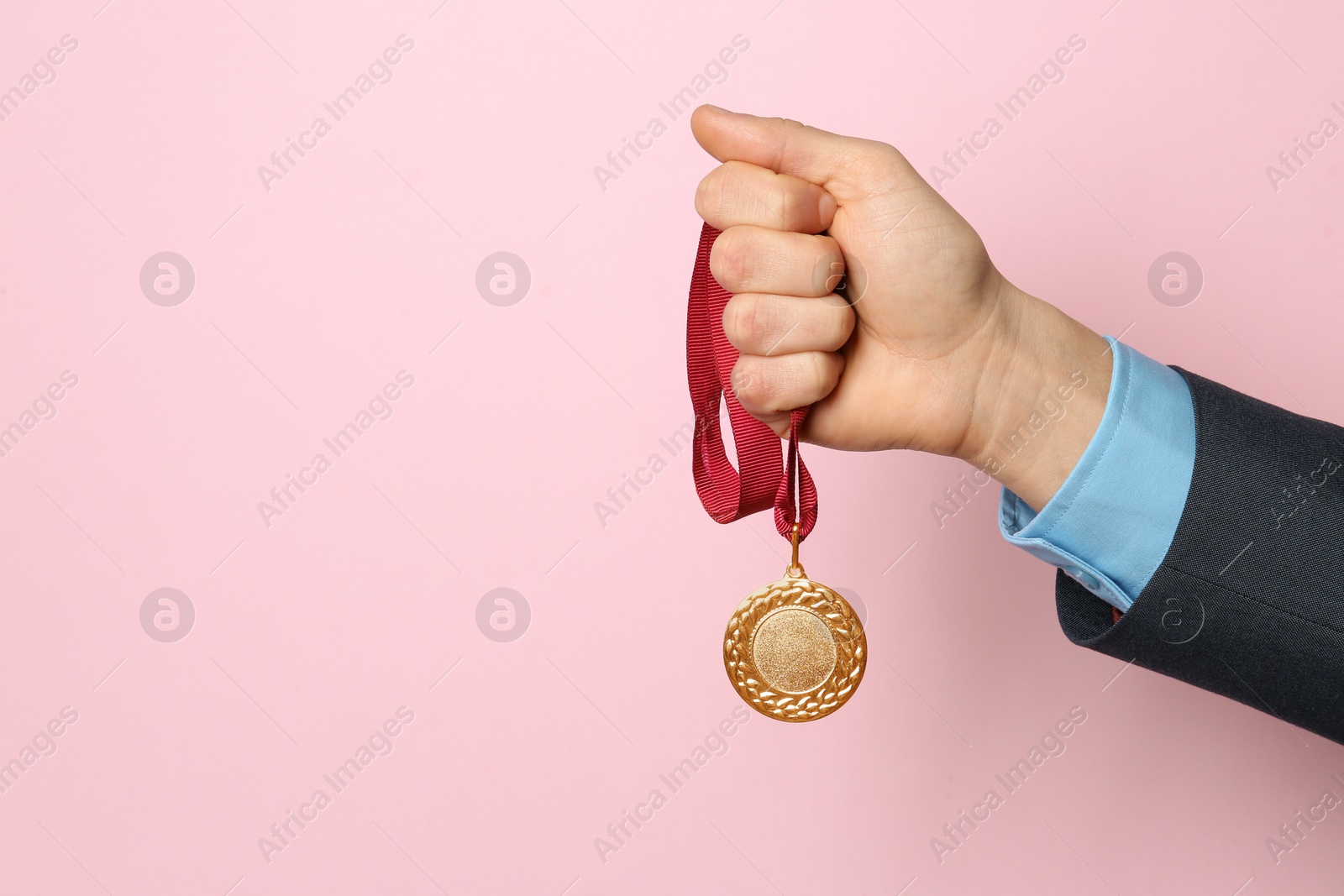 Photo of Man holding golden medal on color background, closeup. Space for text