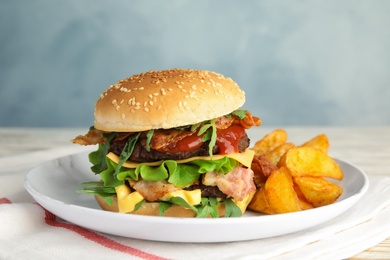 Photo of Tasty burger with bacon and fried potatoes on plate