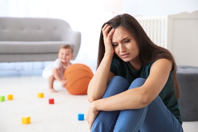 Photo of Young mother suffering from postnatal depression and little baby in room