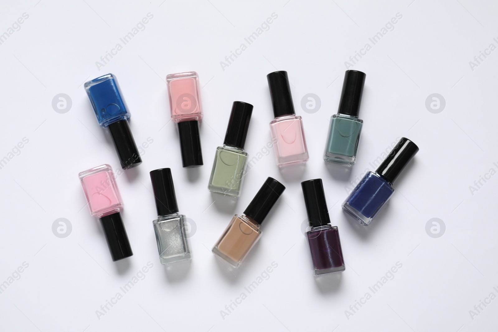 Photo of Nail polishes on white background, flat lay