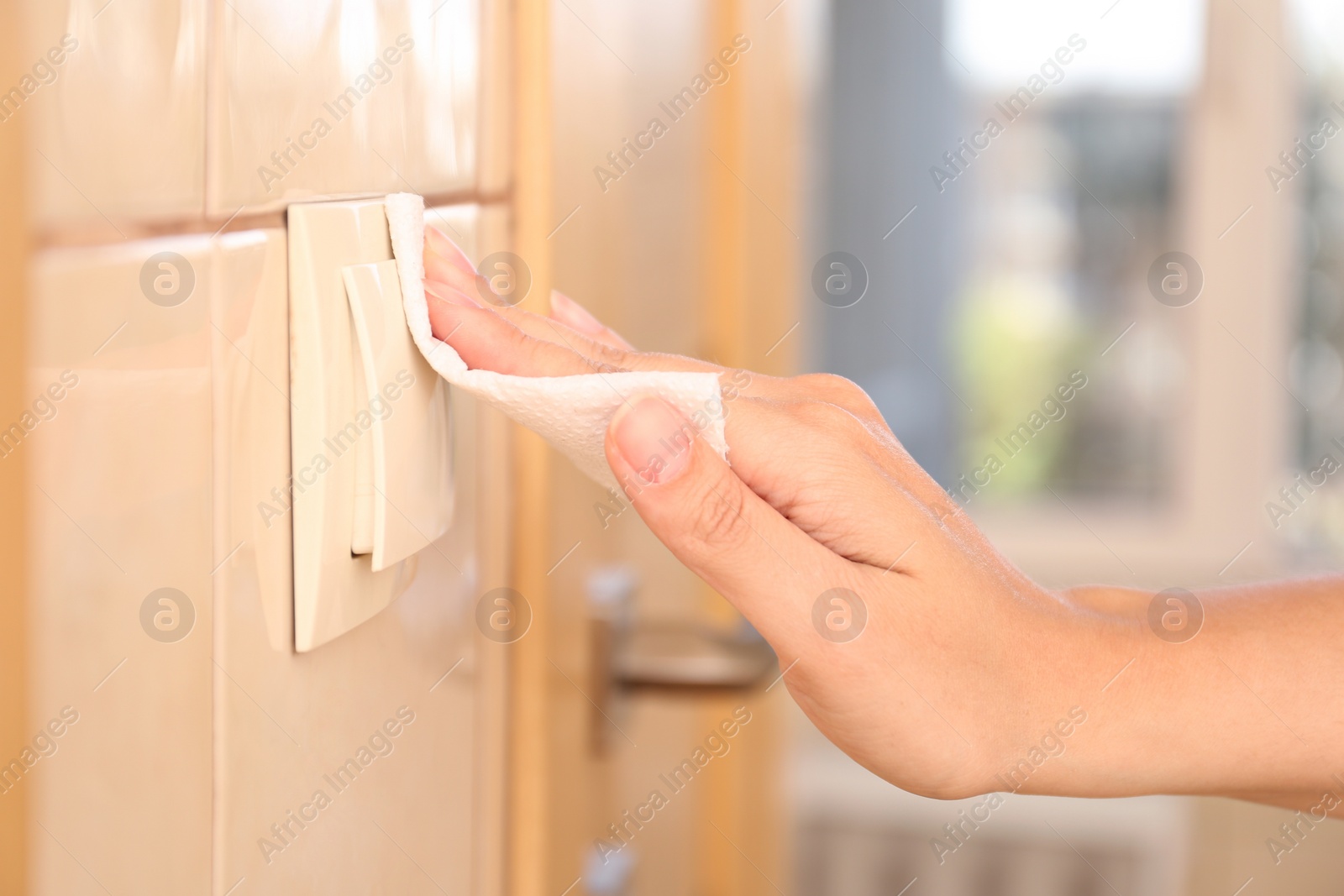 Photo of Woman using tissue paper to switch on light indoors, closeup