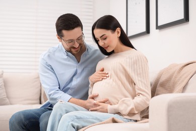 Photo of Pregnant woman spending time with her husband on sofa at home