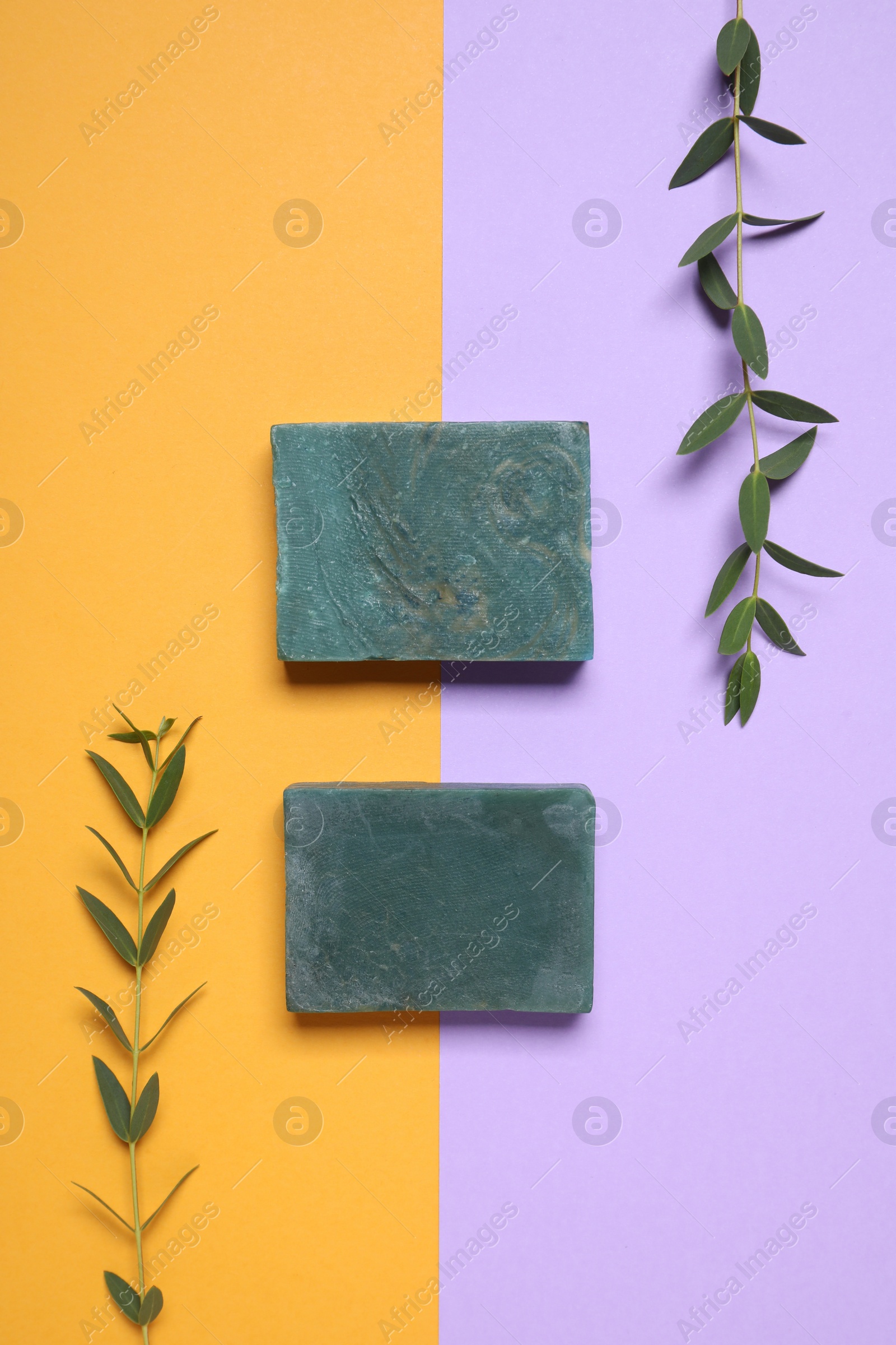 Photo of Bars of organic handmade soap and twigs on color background, flat lay