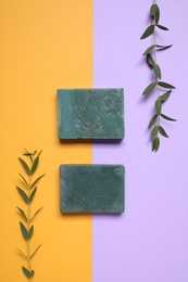 Bars of organic handmade soap and twigs on color background, flat lay