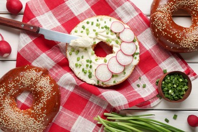 Photo of Delicious bagel with cream cheese, green onion and radish on table, flat lay