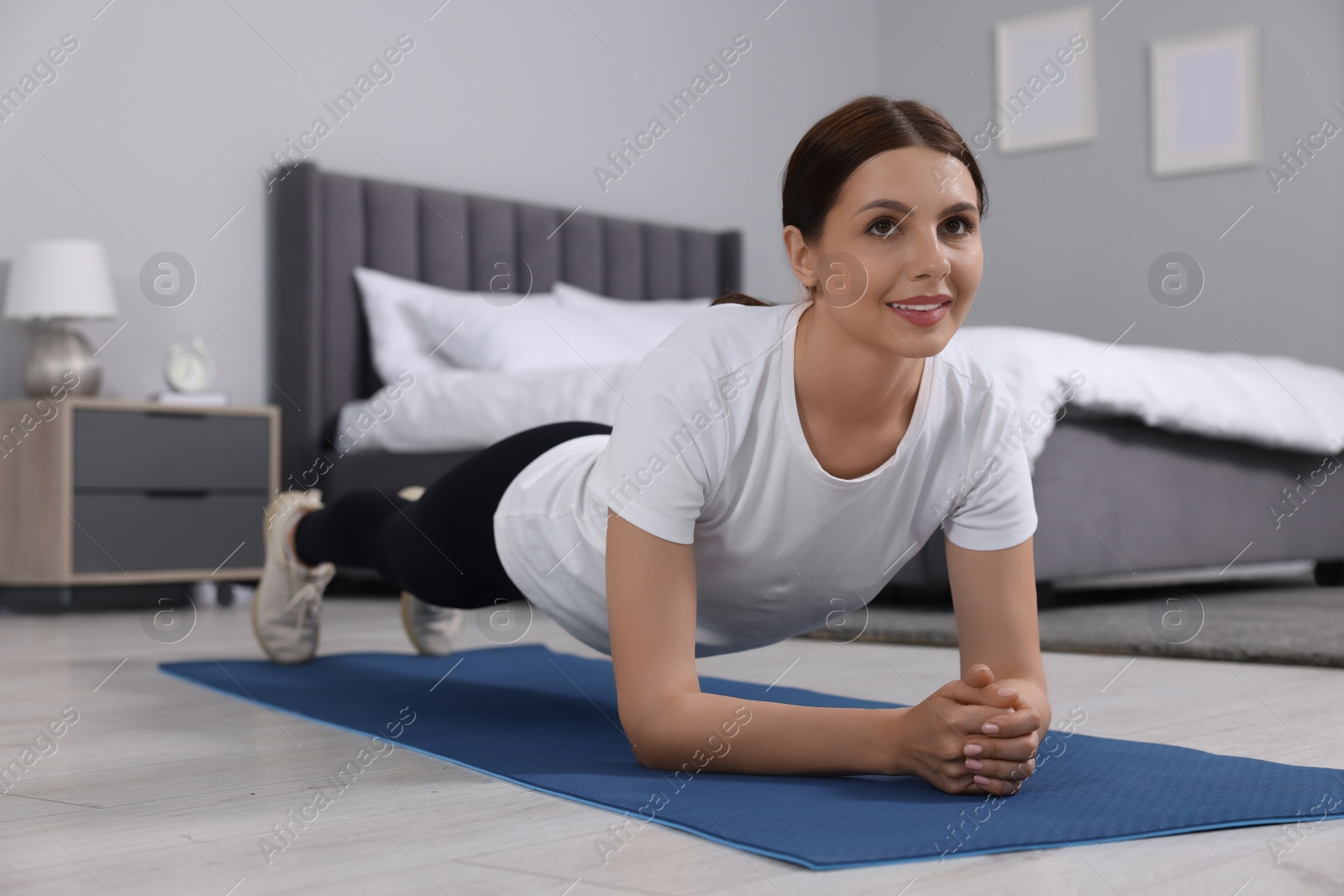 Photo of Happy woman doing plank exercise at home. Morning routine