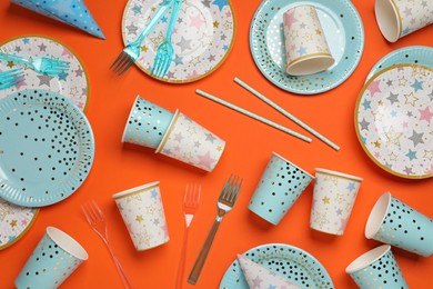 Photo of Disposable tableware on orange background, flat lay