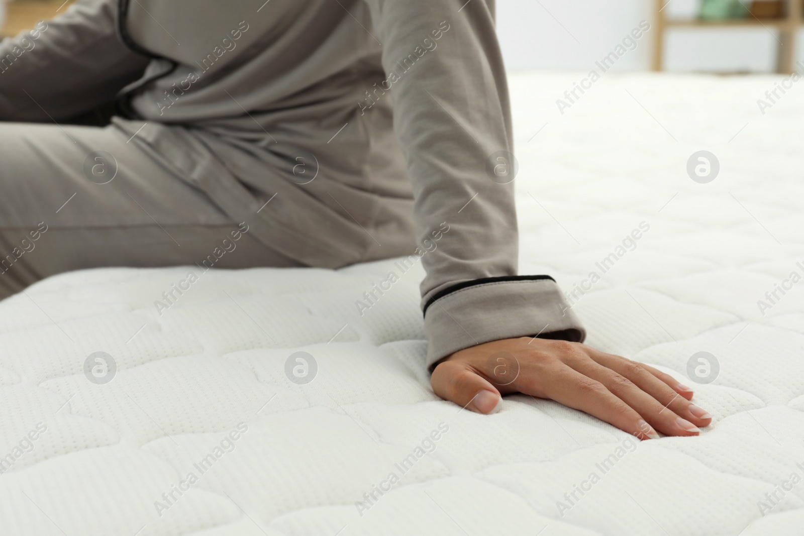 Photo of African American woman sitting on soft mattress in bedroom, closeup