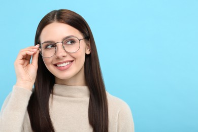 Photo of Smiling woman in stylish eyeglasses on light blue background. Space for text