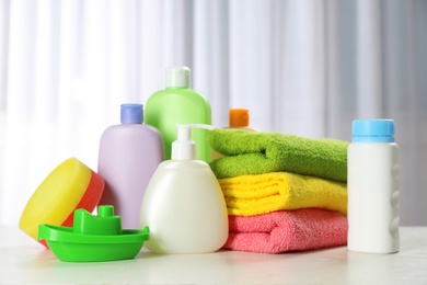 Photo of Baby cosmetic products, toy and towels on table indoors