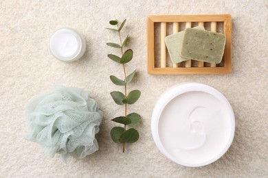 Flat lay composition with moisturizing cream in open jar and other body care products on light textured table