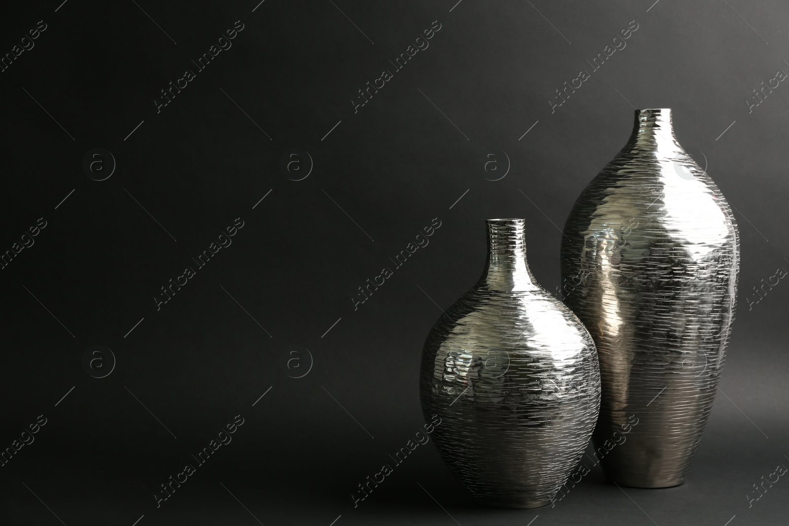 Photo of Stylish silver ceramic vases on black background, space for text