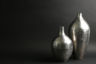 Photo of Stylish silver ceramic vases on black background, space for text