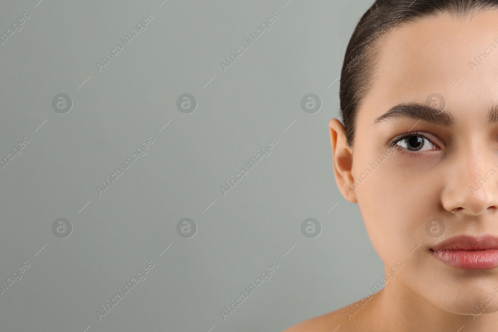 Photo of Young woman with perfect eyebrows on grey background, closeup. Space for text