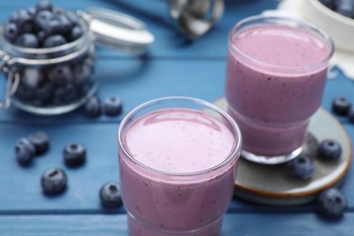 Photo of Tasty blueberry smoothie and fresh berries on blue wooden table, closeup