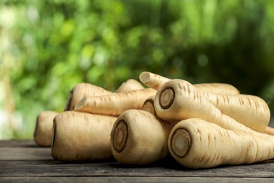 Photo of Delicious fresh ripe parsnips on wooden table outdoors