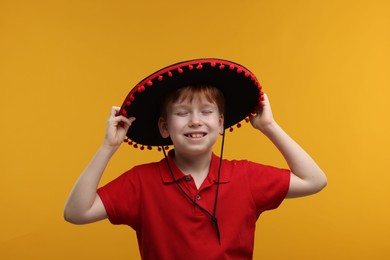 Photo of Cute boy in Mexican sombrero hat on yellow background